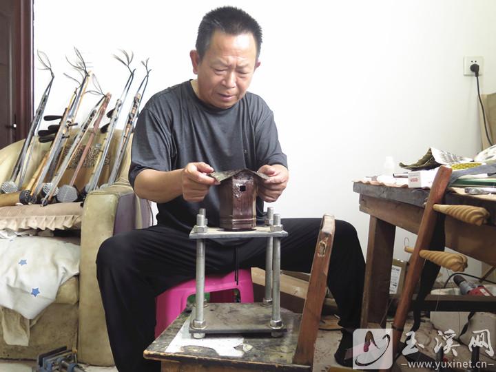 项建国在为二胡琴筒蒙皮子。