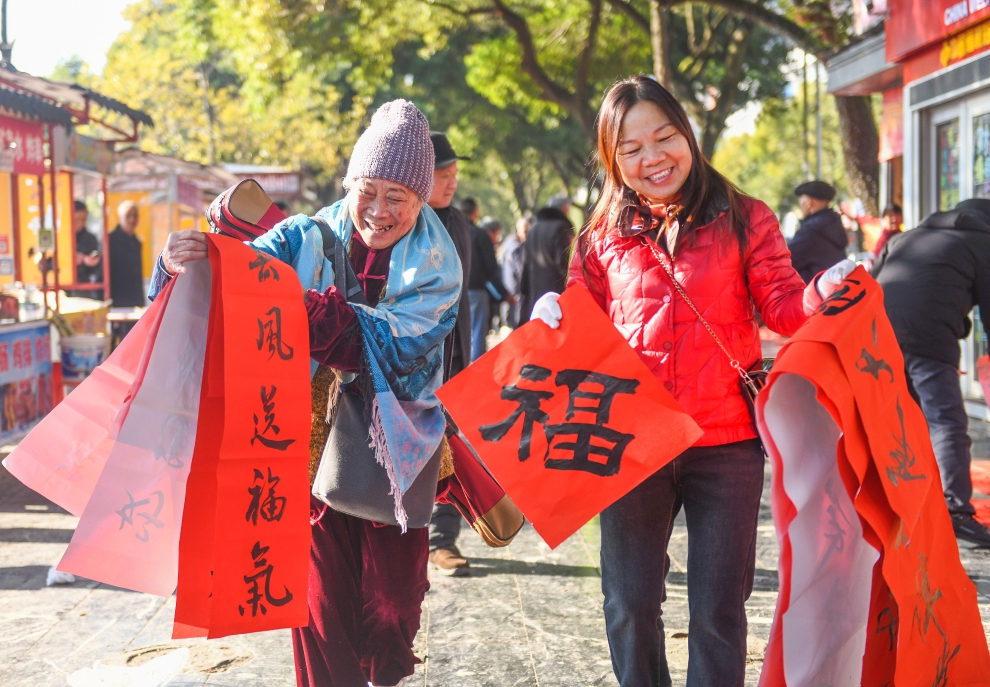 2025年1月13日,在湖南省永州市道县西洲公园义工岗亭,市民们领到了书法志愿者为大家书写的春联。