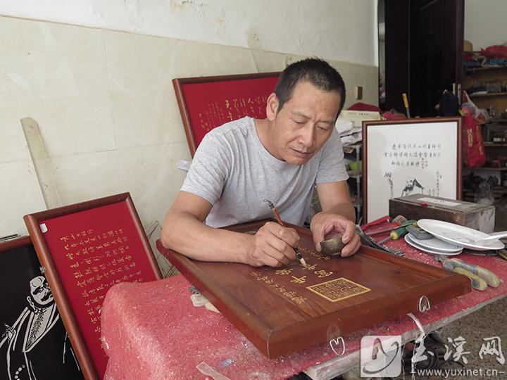 李文为雕刻好的作品描上金粉。